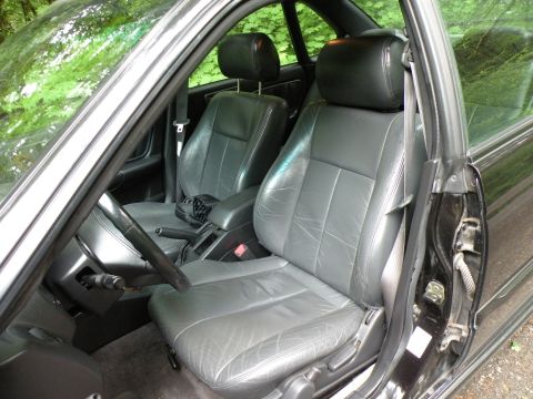 1998 Subaru Legacy - The interior features gray leather seats and a black dashboard, with a view of trees through the windows.