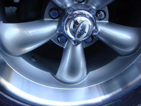 1975 Chevrolet Corvette - A close-up shot focuses on a custom wheel, highlighting its intricate design and a unique center cap emblem.