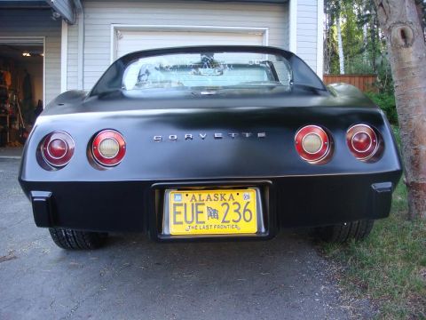 1975 Chevrolet Corvette - The rear of a black 1975 Chevrolet Corvette is shown with its distinctive round taillights and "CORVETTE" badging.