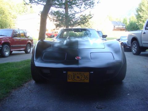 1975 Chevrolet Corvette - Front view of a black 1975 Chevrolet Corvette, a prominent hood scoop and an Alaska license plate.