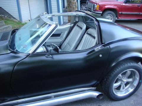 1975 Chevrolet Corvette - A black 1975 Chevrolet Corvette is parked next to a red pickup truck.