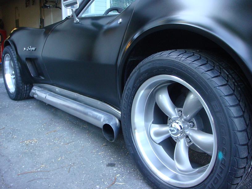Black 1975 Chevrolet Corvette side view with custom wheels and side pipes