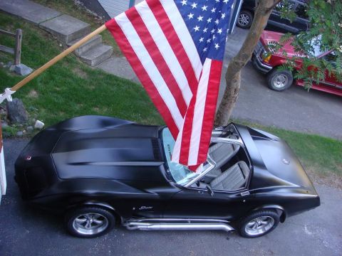 1975 Chevrolet Corvette - A black 1975 Chevrolet Corvette convertible is parked with an American flag flying above it.