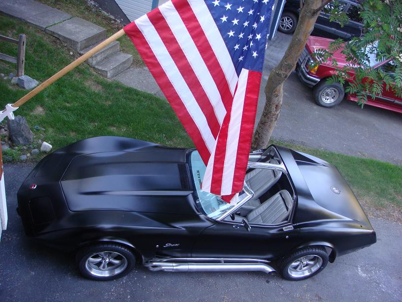Black 1975 Chevrolet Corvette convertible with American flag, 3q-front view
