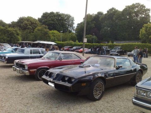 1991 Ford Crown Victoria - A black 1977 Pontiac Firebird Trans Am is parked at an outdoor car show with other vehicles visible.