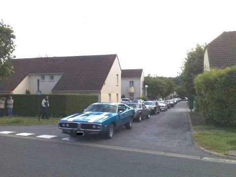 1991 Ford Crown Victoria - A line of classic cars, including a blue and white 1970 Dodge Charger, parked on a residential street.