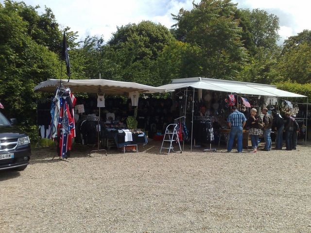 Outdoor market stalls selling clothes and flags, with people browsing