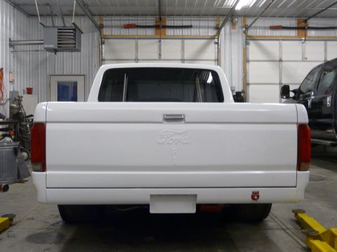 1994 Ford F-150 - The rear of a white 1994 Ford F-150 pickup truck is shown, its distinctive tailgate badging.