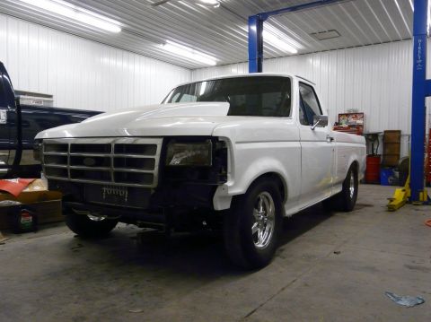 1994 Ford F-150 - White 1994 Ford F-150 pickup truck with a custom hood sits in a garage, partially disassembled.