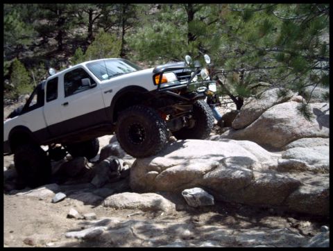 1993 Ford Bronco - Modified 1993 Ford Ranger navigates a rocky trail with its tires on large boulders.