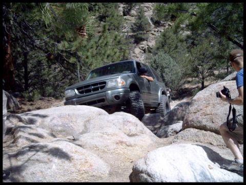 1993 Ford Bronco - A gray Ford Explorer navigates a rocky trail, demonstrating its off-road capabilities.