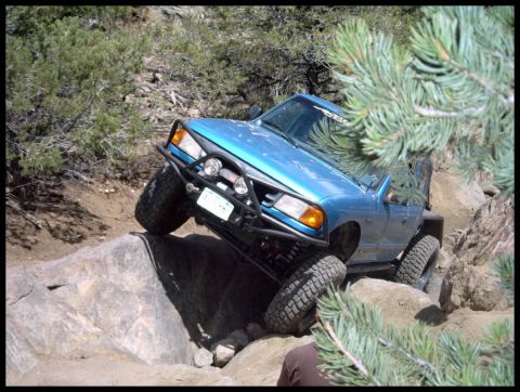 1993 Ford Bronco - A blue 1993 Ford Bronco navigates a rocky trail, demonstrating its off-road capabilities.