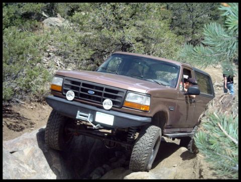 1993 Ford Bronco - This 1993 Ford Bronco is shown tackling a challenging off-road obstacle on a rocky path.