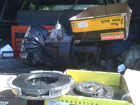 1989 Ford Bronco - Transmission and clutch components are visible in the cargo area of a vehicle, alongside a Craftsman floor jack box and a red toolbox.