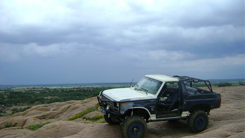 1986 Ford Bronco, two-tone off-road SUV with roll cage on rocky terrain