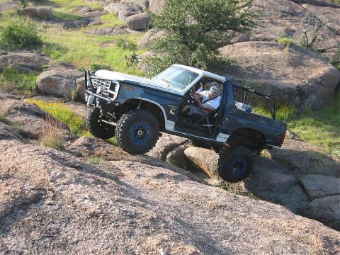 1986 Ford Bronco - Off-road Bronco navigating a challenging rocky trail.