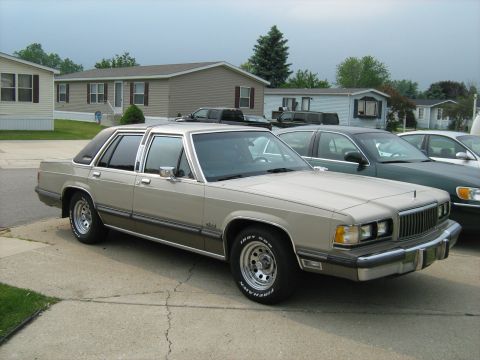 1988 Mercury Grand Marquis - A 1988 Mercury Grand Marquis is seen parked in front of mobile homes, with other vehicles nearby.