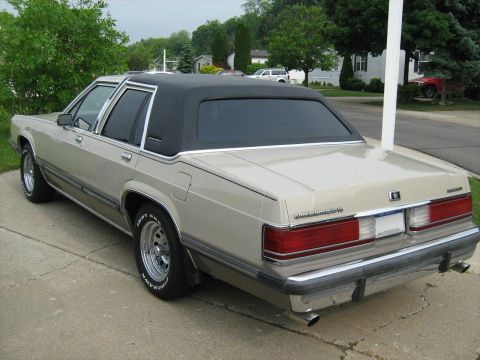 1988 Mercury Grand Marquis - This 1988 Mercury Grand Marquis is seen from the rear quarter angle, showing its tan paint and black vinyl top.