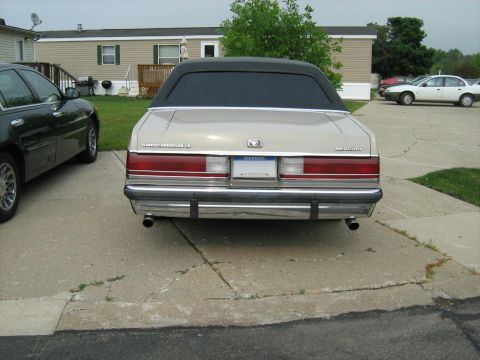 1988 Mercury Grand Marquis - Rear view of a tan 1988 Mercury Grand Marquis with a black vinyl top, parked next to another car.