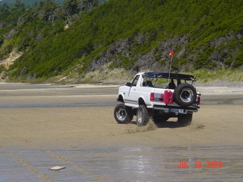 1989 Ford Bronco - This 1989 Ford Bronco is shown driving on a sandy beach with a red flag on its antenna.