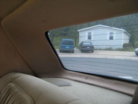 1988 Mercury Grand Marquis - Two vehicles are parked in front of a house, seen from the interior of another vehicle.