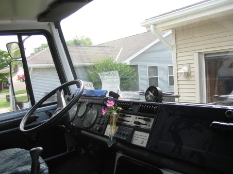 1995 Ford Bronco - The dashboard of a truck cab, a steering wheel and various gauges, with houses visible through the windshield.