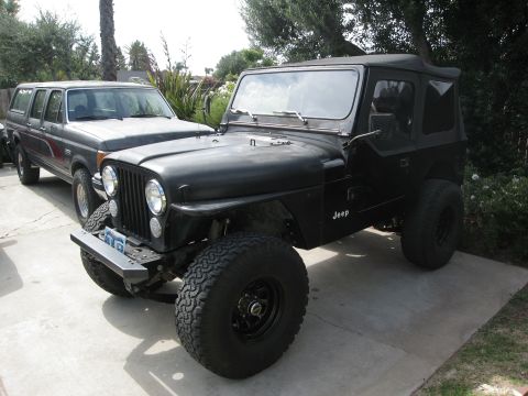 1986 Ford Bronco - Two vehicles parked outside: a black Jeep CJ and a gray Ford Bronco.