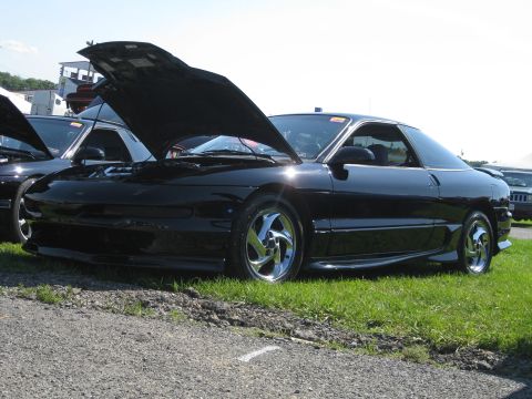1994 Ford Probe - A black coupe, likely a 1993 model, is displayed with its hood open, alongside other vehicles.