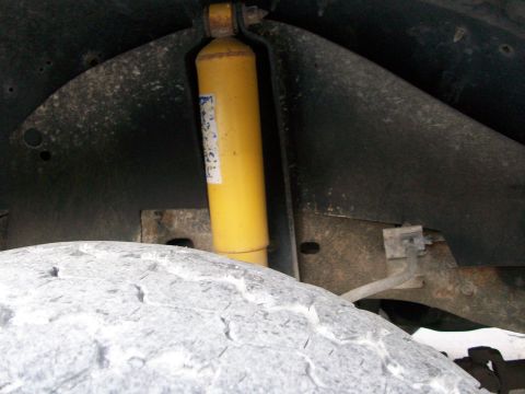 1995 Ford C-350 (Centurion Conversions) - Close-up view of a yellow shock absorber and tire tread within the wheel well of a vehicle.