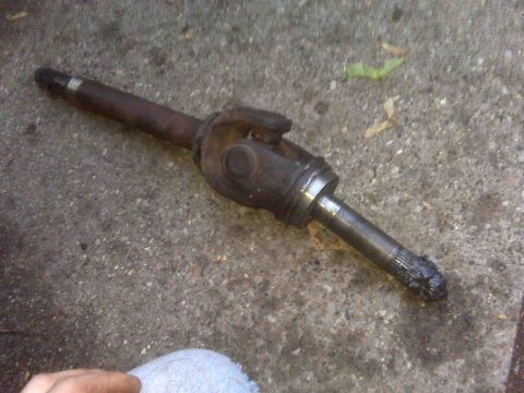 1995 Ford Bronco - Close-up of a used driveshaft U-joint assembly resting on a concrete surface.