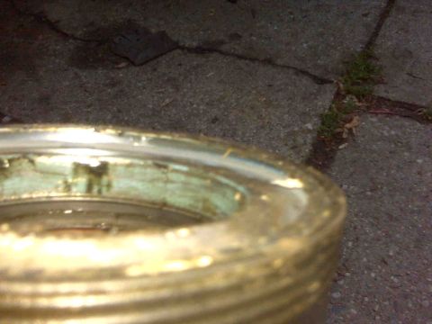 1995 Ford Bronco - A close-up view of a damaged gold wheel hub with green corrosion is shown against a cracked asphalt background.