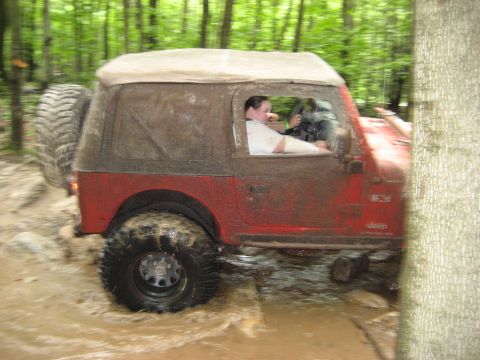 1991 Ford Bronco - Jeep Wrangler navigates a challenging muddy off-road course during a spring event.
