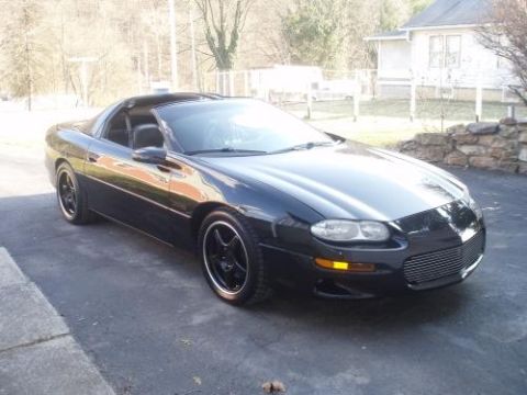 2002 Chevrolet Camaro - This black Chevrolet Camaro is parked in a driveway with a house and trees in the background.