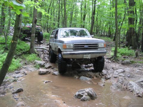 1991 Ford Bronco - A 1991 Ford Bronco tackles a challenging off-road course, splashing through water and over rocks.