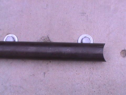 1997 Ford Ranger - A metal pipe section is attached to a concrete surface with two bolts.
