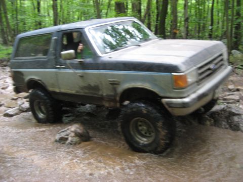 1991 Ford Bronco - 1991 Ford Bronco navigating a rocky stream during an off-road event.