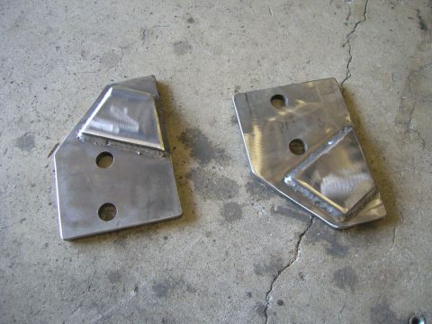 1996 Ford Bronco - Two custom metal brackets, likely for automotive modification, shown on a concrete surface.