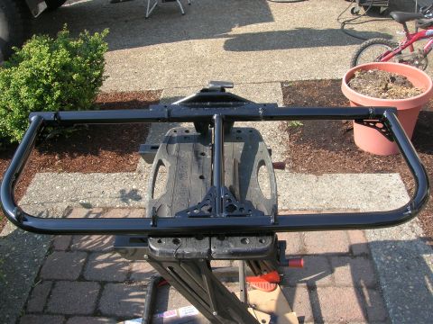 1996 Ford Bronco - A black metal bull bar is shown mounted on a stand, with a bicycle and planter visible in the background.