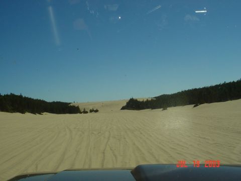 1989 Ford Bronco - View from inside a vehicle driving through sand dunes on a sunny day, with a date stamp visible.