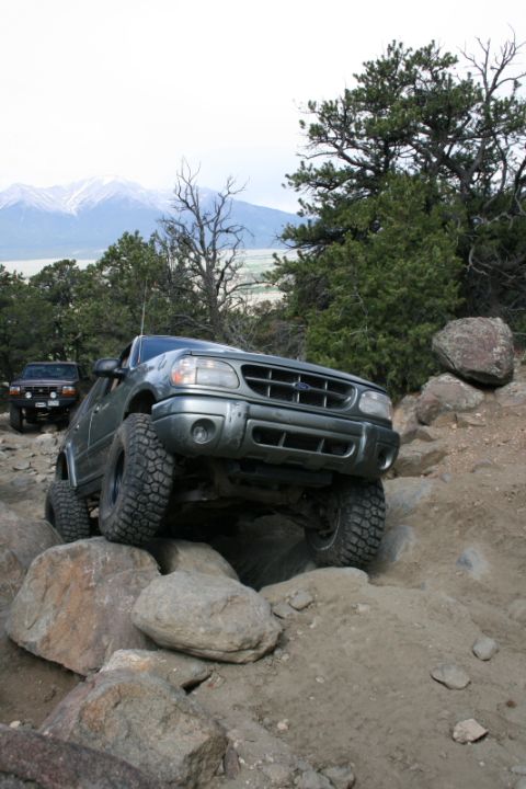 1993 Ford Bronco - An off-road vehicle navigates a rocky terrain with mountains in the background.