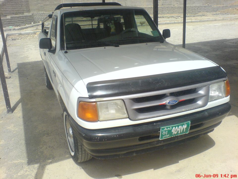White Ford Ranger pickup truck parked under a shelter. Green license plate visible