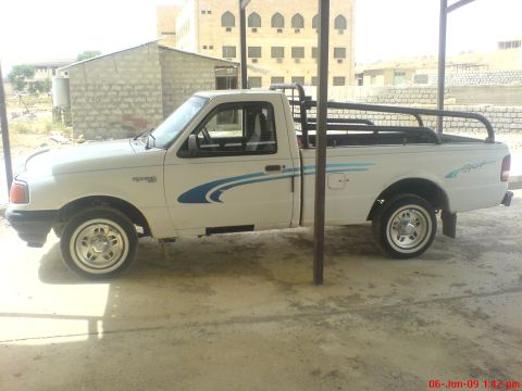 1992 Ford Crown Victoria - This white Ford Ranger pickup truck is seen from the side under a covered area.