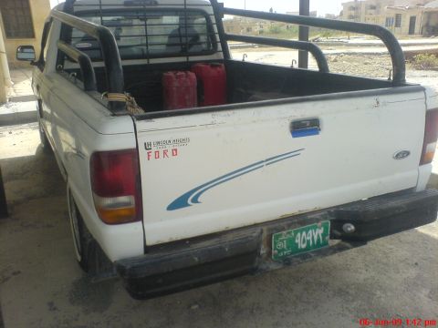 1992 Ford Crown Victoria - Rear view of a white Ford pickup truck with a roll bar and two red gas cans in the bed.