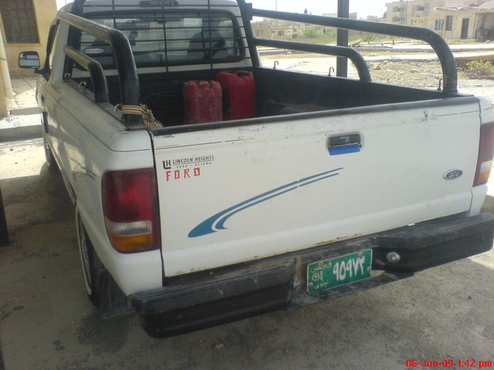 White Ford pickup truck rear view with two red gas cans in bed