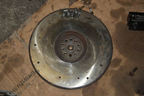 1994 Ford Bronco - A vehicle's flywheel and several spark plugs are laid out on a wooden surface, possibly during a repair or maintenance session.