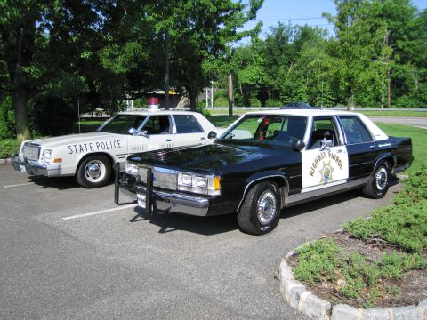 1991 Ford LTD Crown Victoria - black-and-cream California Highway Patrol Ford sedan sits alongside a Rhode Island State Police car on a parking lot.