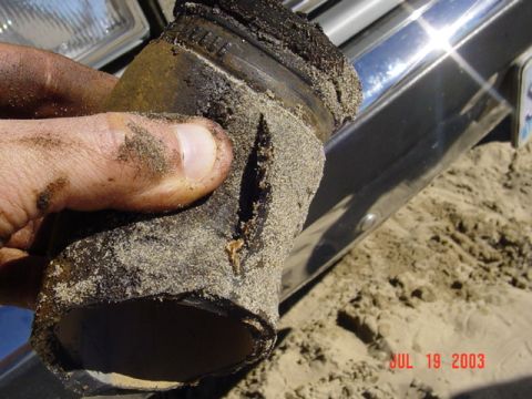 1989 Ford Bronco - A hand holds a damaged hose against a vehicle's chrome bumper and headlight, with a date stamp of July 19, 2003.