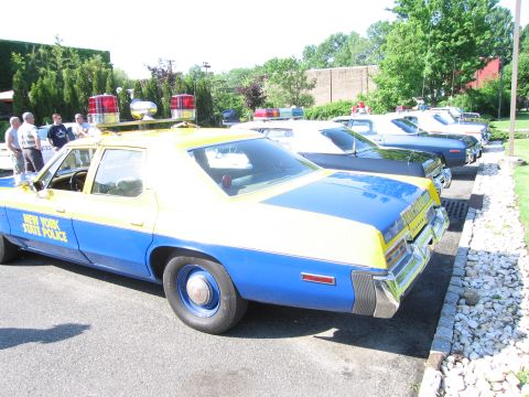 1991 Ford LTD Crown Victoria - rear quarter of a blue-and-yellow New York State Police vintage sedan in a lot lined with other classic patrol cars.