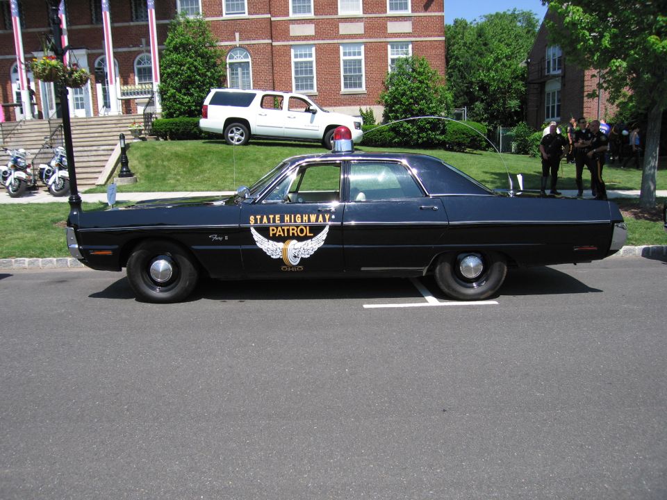 Side view of black State Highway Patrol sedan with winged emblem and roof light