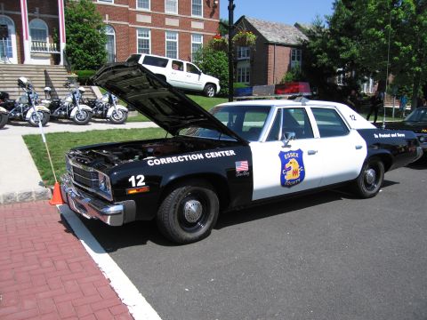1991 Ford LTD Crown Victoria - black-and-white Essex County Correction Center police car, number 12, displayed with its hood raised near parked motorcycles.